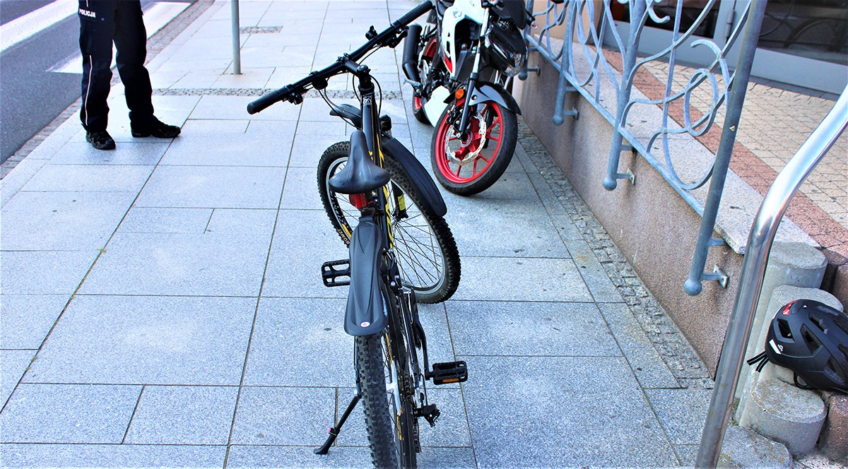 Nastoletni rowerzysta rowerem przed motocyklistę na przejściu dla pieszych